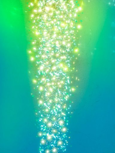 Chorro de luces brillantes en un fondo azul y verde, con destellos y un efecto etéreo.